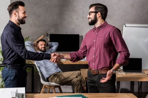 smiling-businessmen-shaking-hands-in-office-SMHFN47.jpg